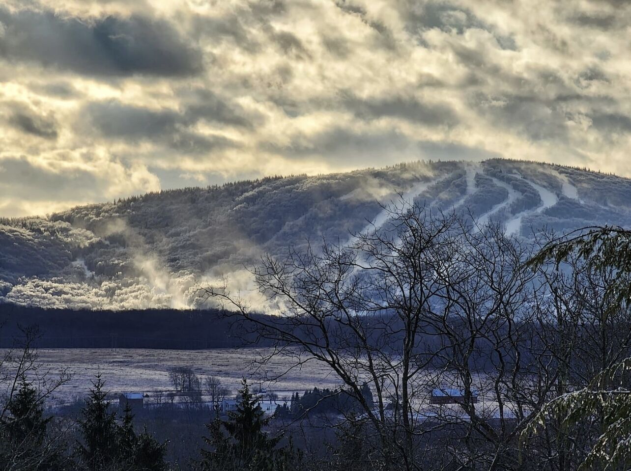 Een bergachtig landschap met een heldere lucht en een met sneeuw bedekte pad dat de heuvel op leidt.
