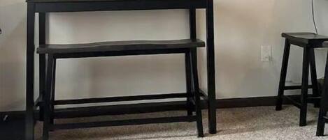 A room with a flat-screen TV mounted on the wall, a black TV stand, and a wooden cabinet.