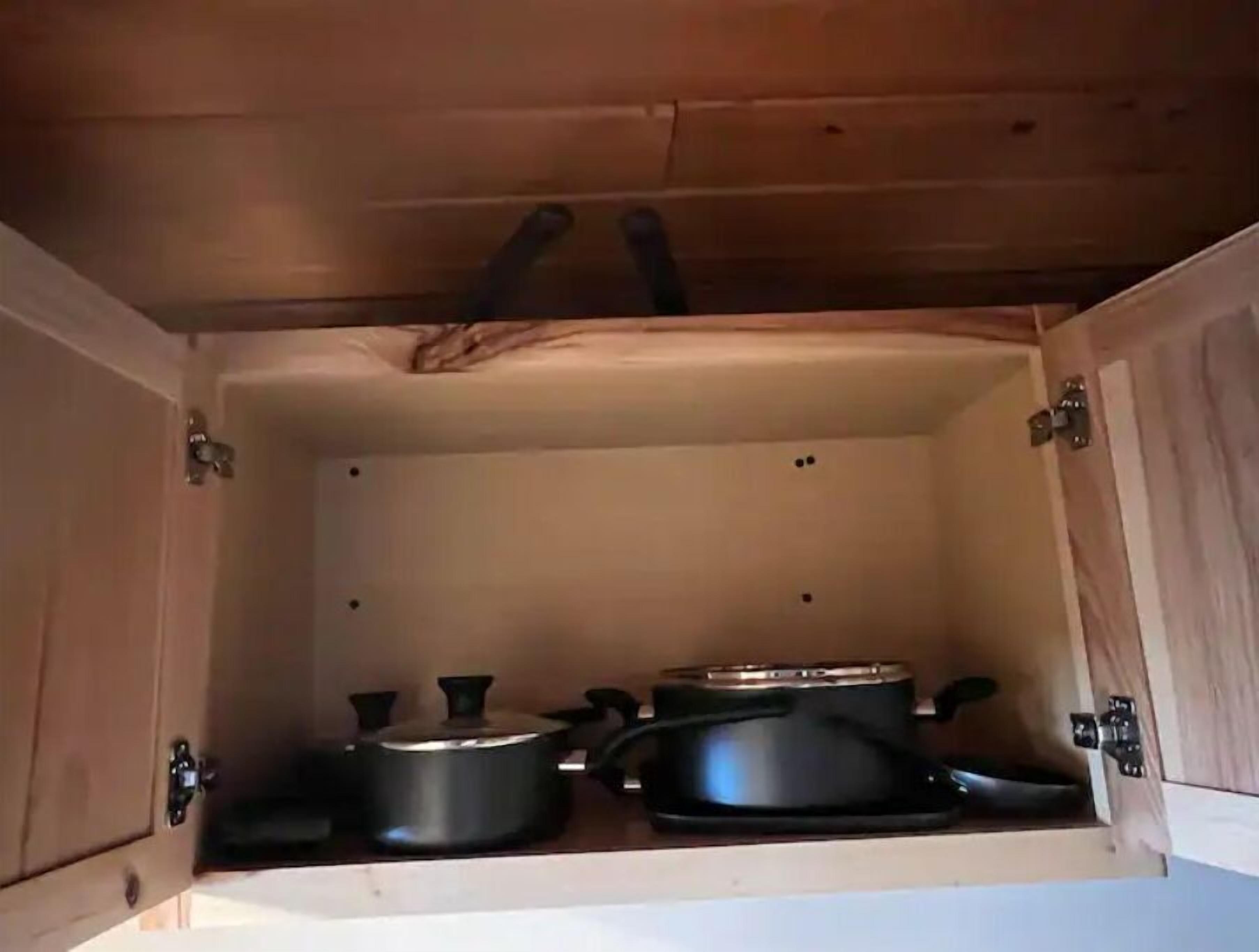 Ett träskåp med två svarta krukor och en stekpanna.