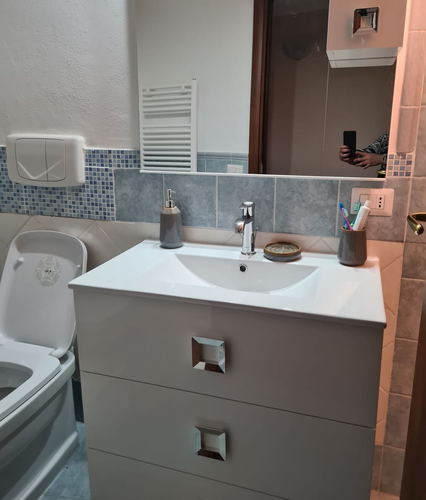 A bathroom with a white sink, a mirror, and a toilet.