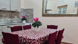 A dining area with a round table covered by a patterned tablecloth, surrounded by matching chairs. There is a potted plant with pink flowers on the table. - Pretty apartment in the center of Vasanello (VT), close to all services (Vasanello)