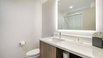 A modern bathroom with a white sink, a mirror, and a toilet.