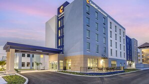 Un hotel moderno con un llamativo letrero de 'Comfort Inn & Suites', una entrada bien iluminada y un área ajardinada con una pequeña piscina.