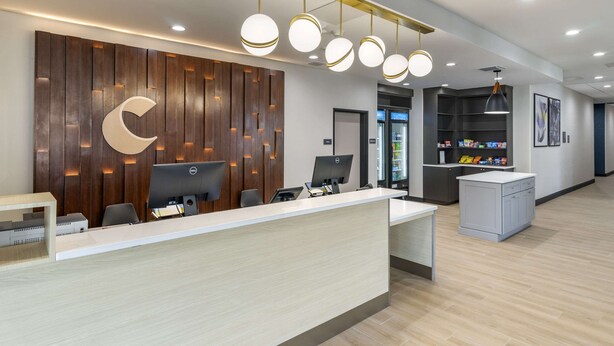 Una moderna zona de recepción con un panel de madera, un diseño en forma de media luna y un mostrador con computadoras.