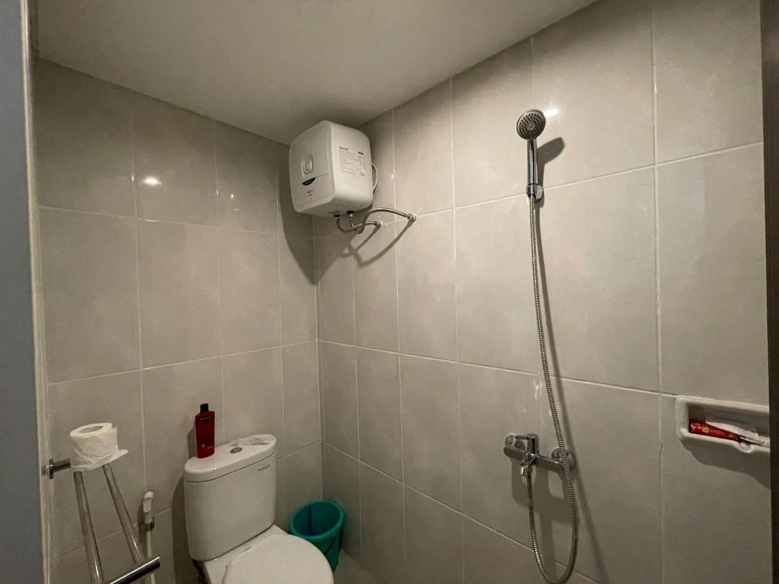 A small bathroom with a toilet, a shower, and a toilet paper holder.