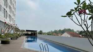 A rooftop swimming pool with a clear view of the surrounding buildings and a covered seating area. - Serpong Garden Apartment by Kakarama (Cisauk)