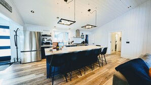 Et moderne køkken med en central ø, rustfrie hvidevarer og trægulv.