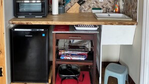 Une cuisine compacte équipée d’un four encastré, d’un mini-réfrigérateur et d’un évier.