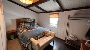 Une chambre avec un lit, un banc, une fenêtre et un lit superposé.