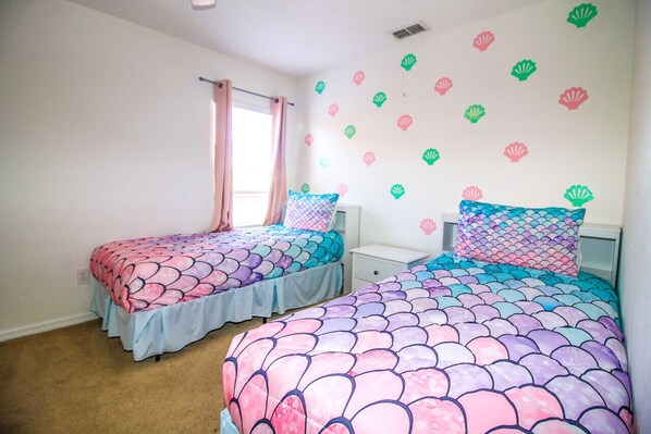 A bedroom with two beds, each with a unique patterned bedspread.