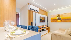 Una sala de estar moderna con comedor, que incluye un televisor de pantalla plana, obras de arte y un sofá.