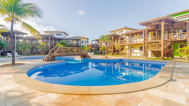 Un resort con piscina central, varias villas para huéspedes y una zona de terraza de madera.