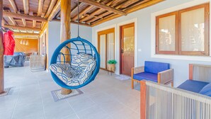 Un amplio espacio interior con una silla colgante azul, un sofá azul y una estructura de techo de madera.
