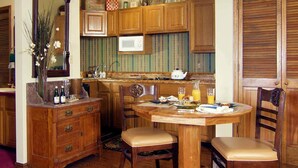 A wooden kitchen with a dining table and chairs, a microwave, and various kitchen items.