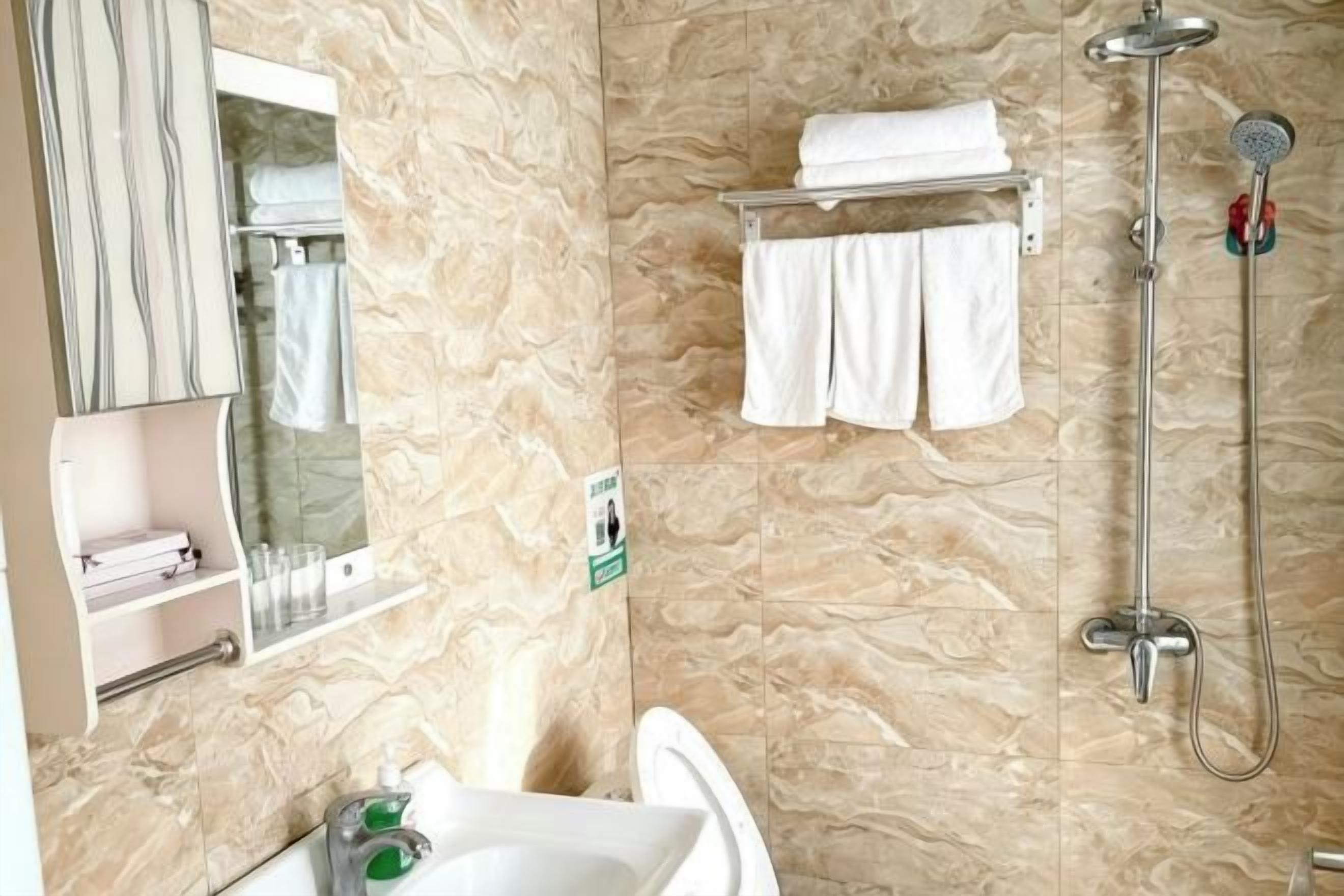 Ein Badezimmer mit Waschbecken, Spiegel, Handtuchhalter und Dusche.