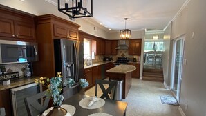 A modern kitchen with wooden cabinets, stainless steel appliances, and a dining area with a bench and placemats.