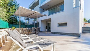 Un área de estar moderna al aire libre con sillones de descanso y un porche cubierto.