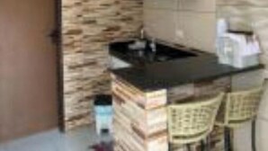 A compact kitchen with a stone wall backsplash, a black countertop, and a small bar area with two chairs. - 1 Family and cozy apartment (Maragogi)