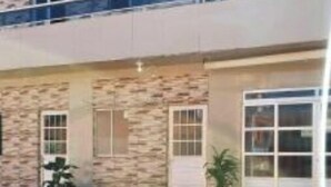 A two-story building with a stone facade and multiple windows. - 1 Family and cozy apartment (Maragogi)