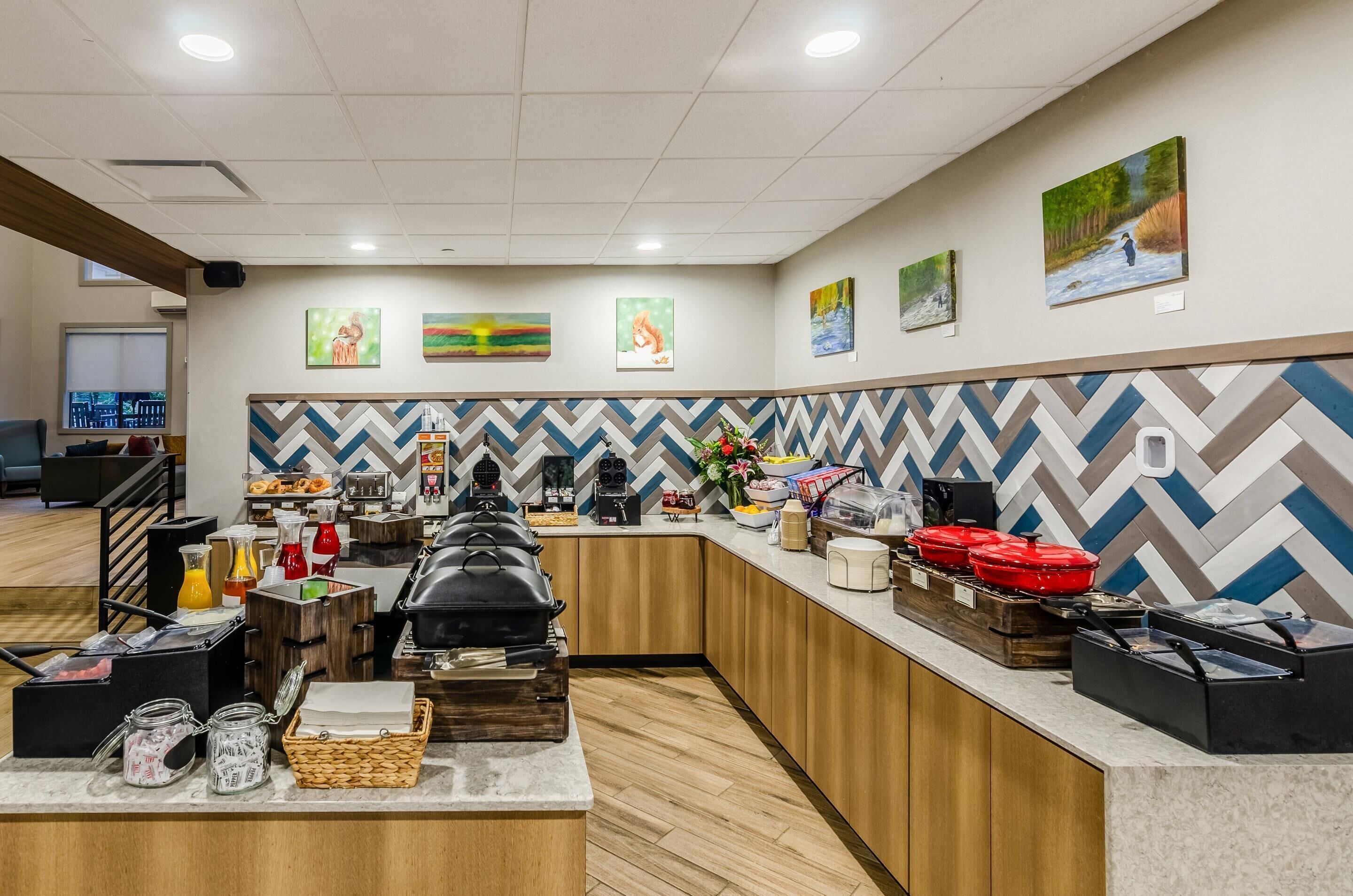 A hotel breakfast area with a buffet setup, including various food items and condiments.