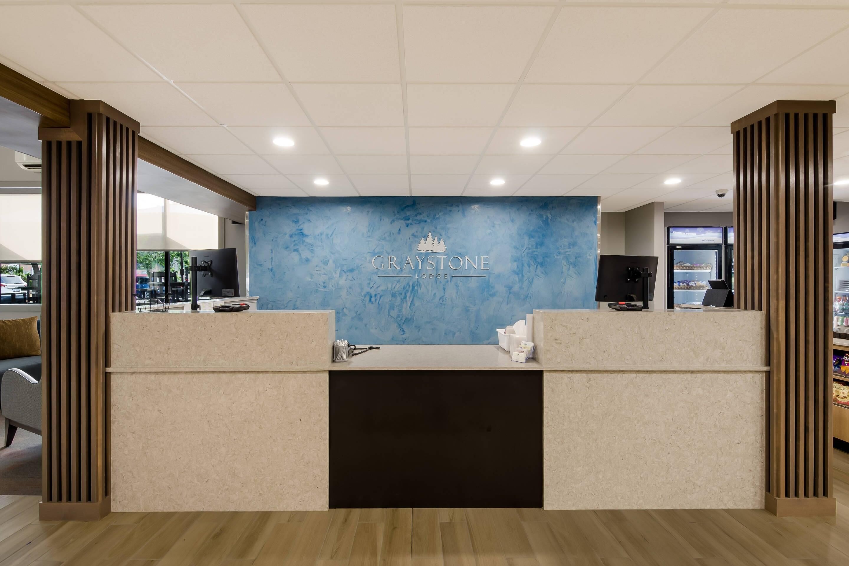 A reception desk with a blue marble wall and the name "GRAYSTONE LODGE" in the center.