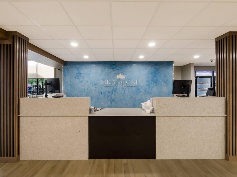 Un mostrador de recepción con una pared de mármol azul y el nombre "GRAYSTONE LODGE" en el centro.