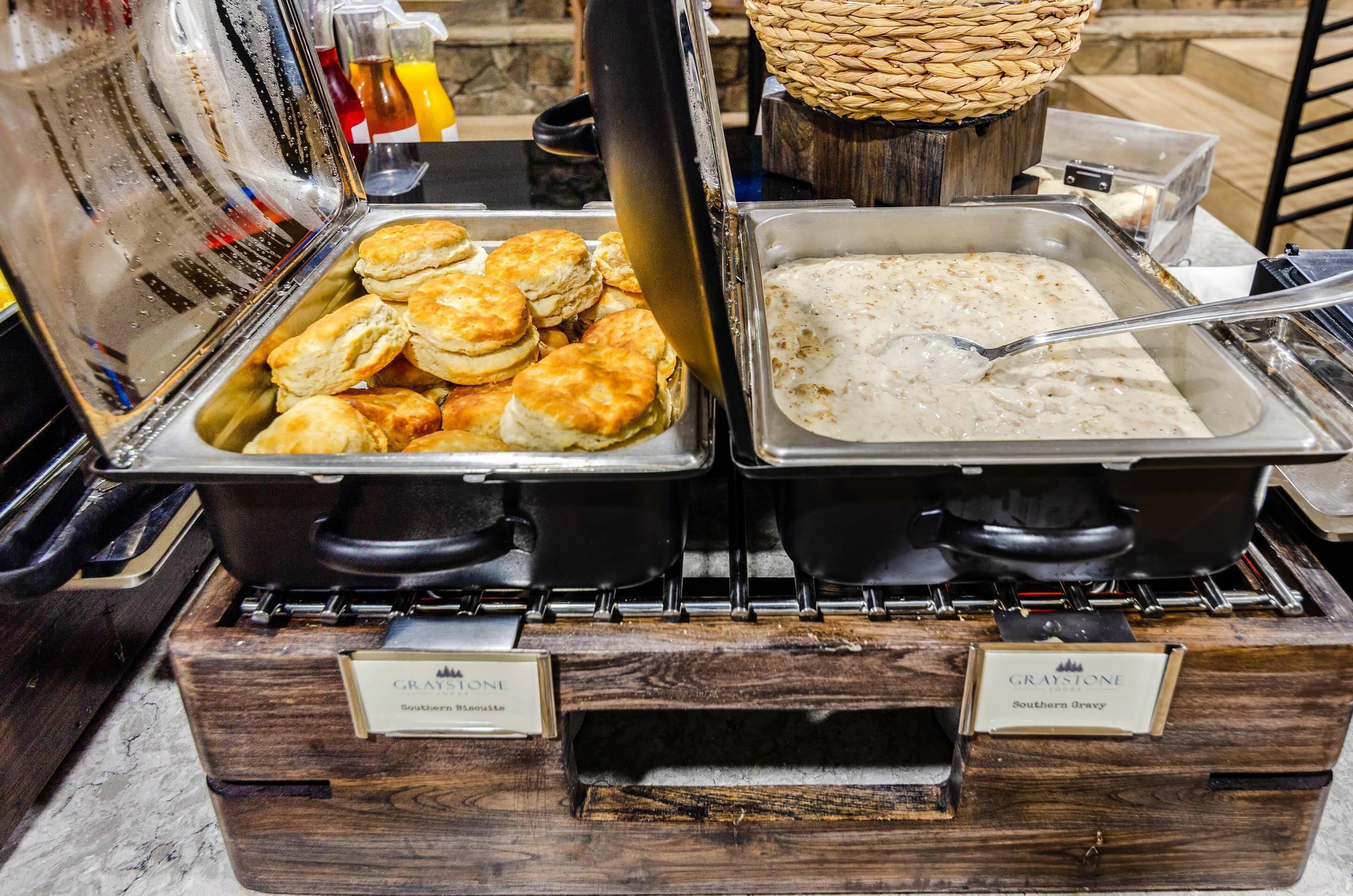 Un buffet con vassoi di biscotti e salsa gravy, e un cesto di condimenti.