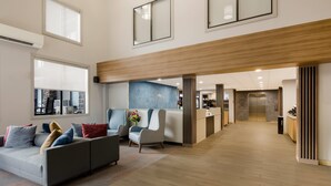 A spacious lobby with a grey sofa, a reception desk, and a wooden ceiling.