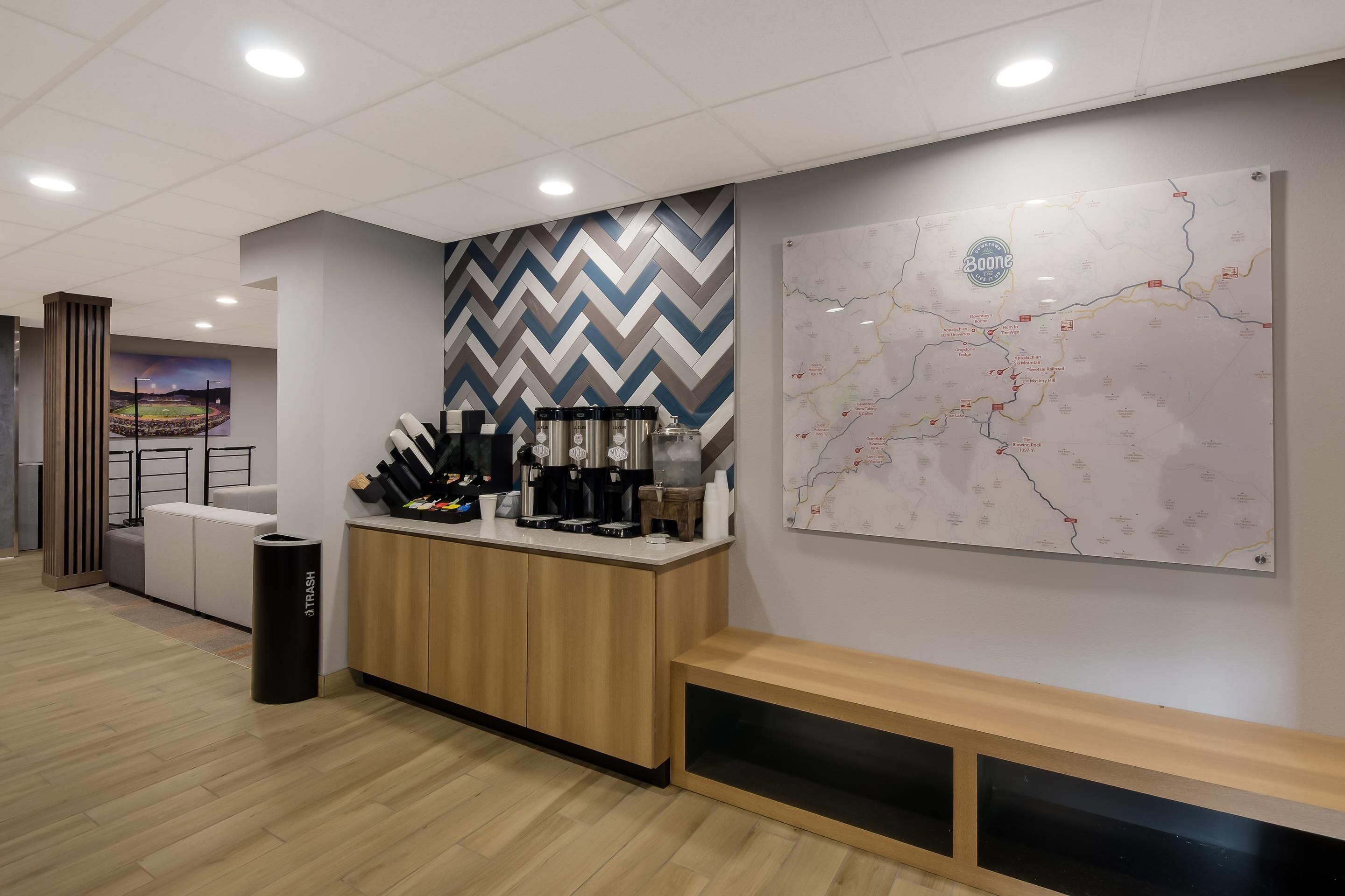 A modern reception area with a wooden counter, coffee machines, and a map on the wall.