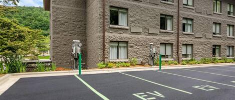 Un edificio con espacios de estacionamiento para vehículos eléctricos y fachada de piedra.