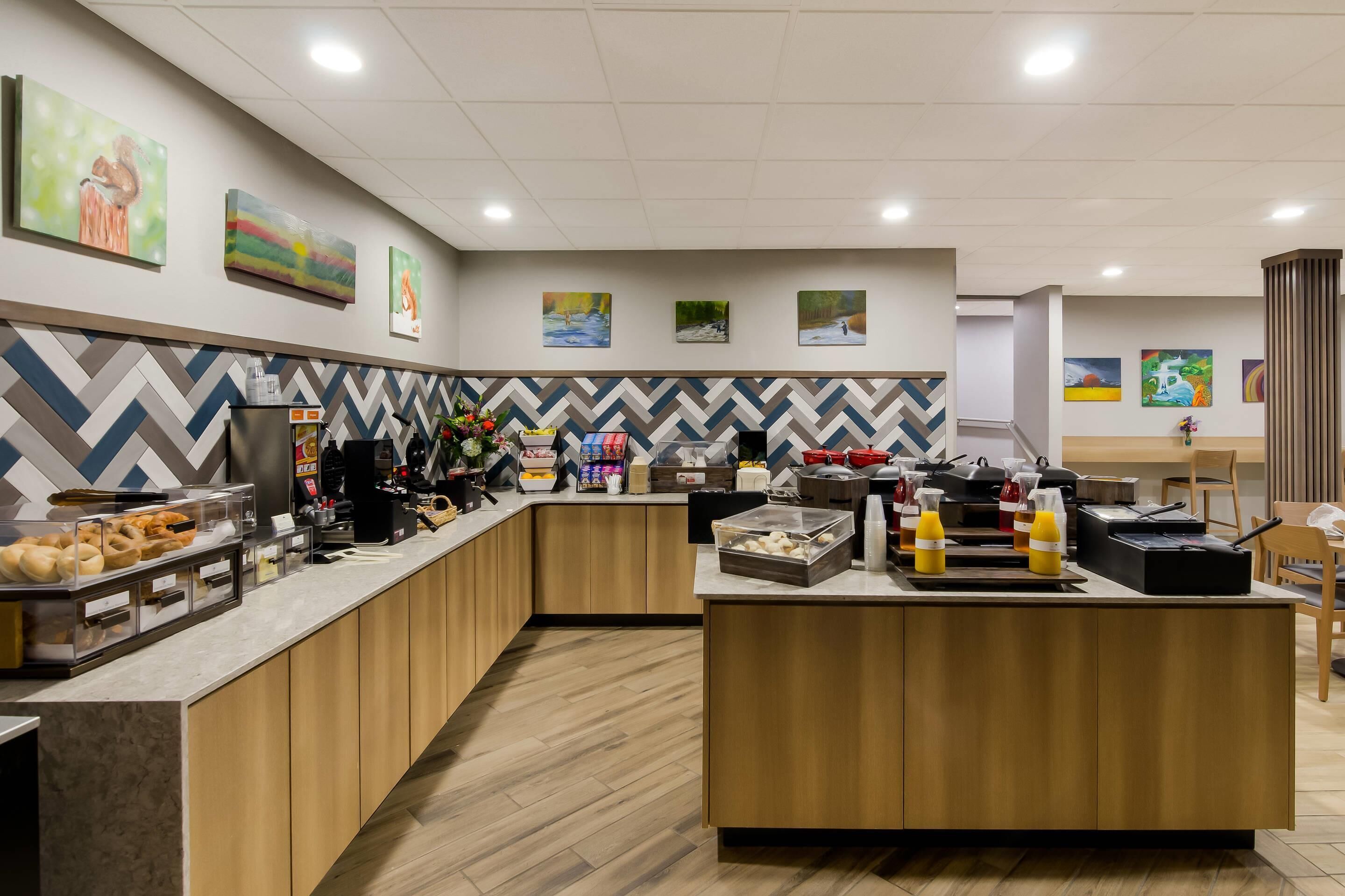 Una cocina de hotel moderna con una zona de bufé, armarios de madera y un salpicadero con estampado de espiga.
