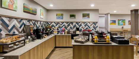 Una cocina de hotel moderna con una zona de bufé, armarios de madera y un salpicadero con estampado de espiga.