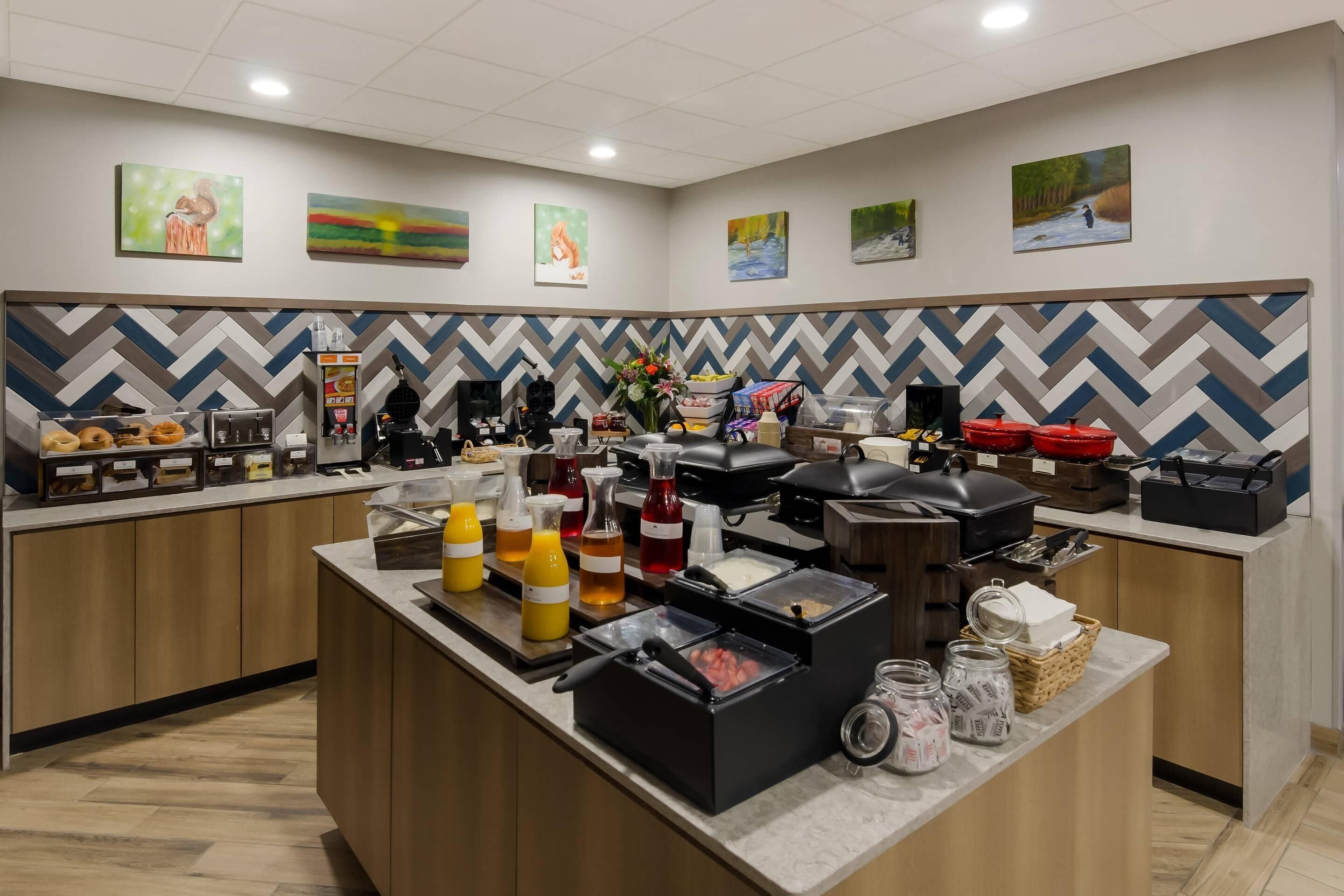 A hotel breakfast area with a buffet setup, including various food items and beverages.