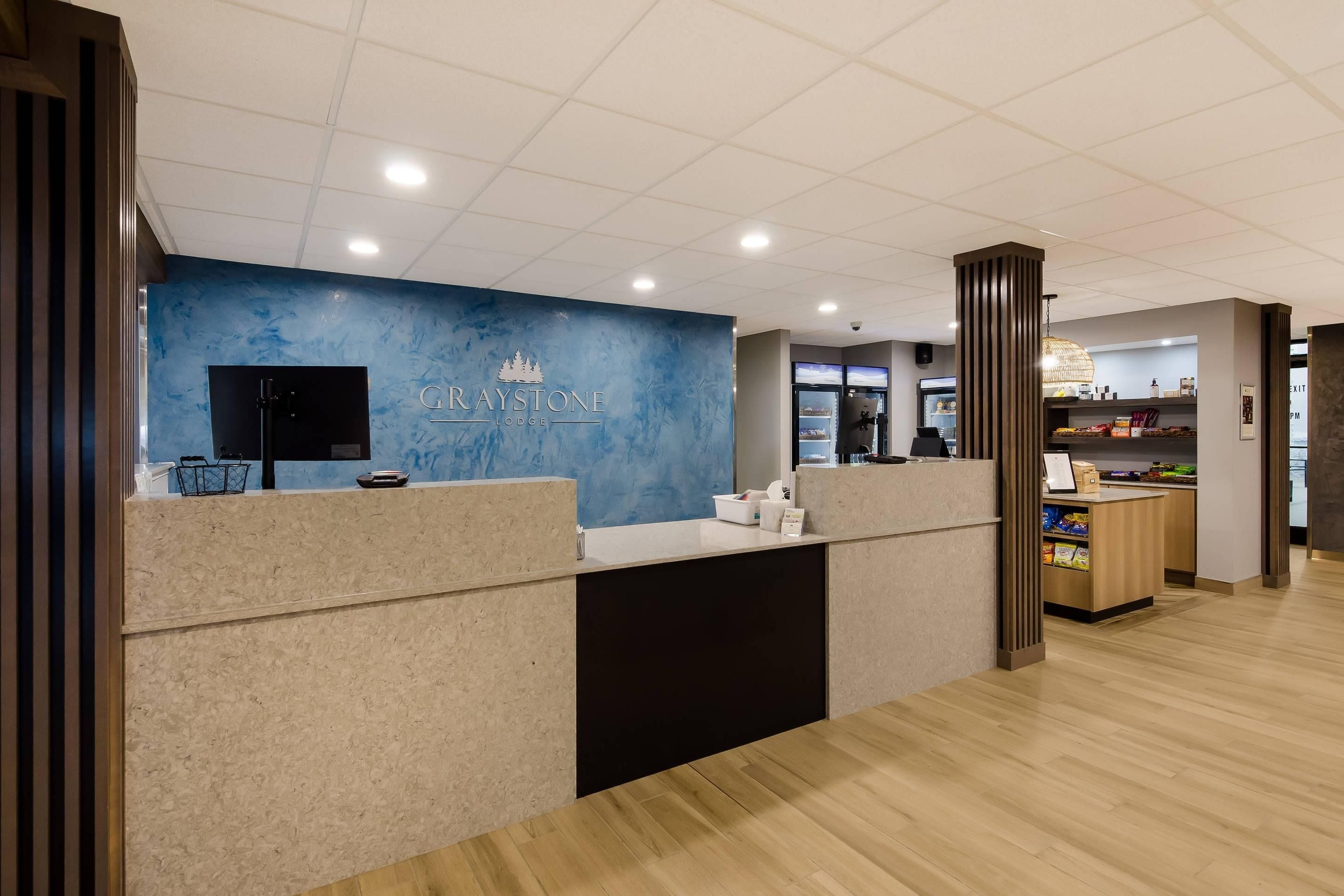 Zona de recepción con pared azul, mostrador de recepción, televisor y un mostrador con aperitivos.