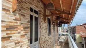 Un balcon fermé doté d’une façade en pierre, de poutres en bois et d’une rambarde en métal.