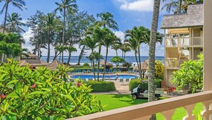 A resort with a pool, palm trees, and a view of the ocean.