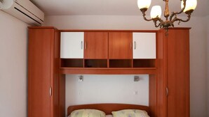 Ein Schlafzimmer mit einem Bett, einem Holzschrank und einer Klimaanlage.
