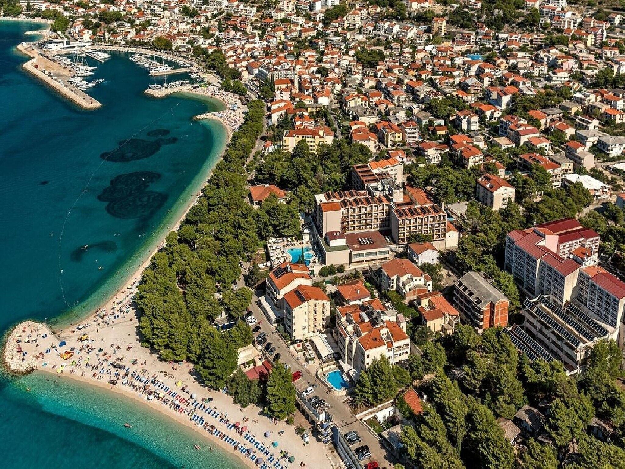 An aerial view of a coastal town with a marina, beach, and residential buildings.