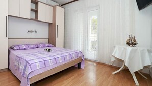 A bedroom with a bed, a wardrobe, a table with a ship model, and a TV on the wall. - Apartments Pezo - Two Bedroom Apartment with Balcony (Baška Voda)