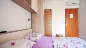 A bedroom with a bed, a wooden door, and a wall-mounted air conditioning unit.