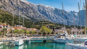 A marina with boats docked, surrounded by a mountainous landscape and residential buildings.