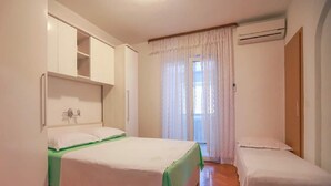 A bedroom with a bed, a smaller bed, a wardrobe, and an air conditioning unit.