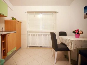Cozy room with a kitchenette, dining area, and a window with shutters.