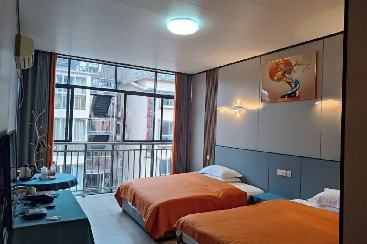 Habitación de hotel con dos camas, un balcón, un ventanal grande y un cuadro en la pared.