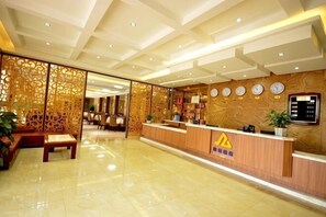 A hotel reception area with a wooden reception desk, a clock, and a plant. - Xiannv Mountain Wanghao Hotel (Chongqing)