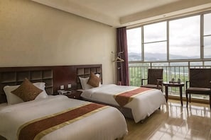 Habitación de hotel con dos camas, un balcón y vistas al exterior.