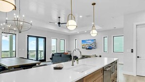 Een moderne keuken met een groot eiland, hanglampen en uitzicht op het buitengebied.