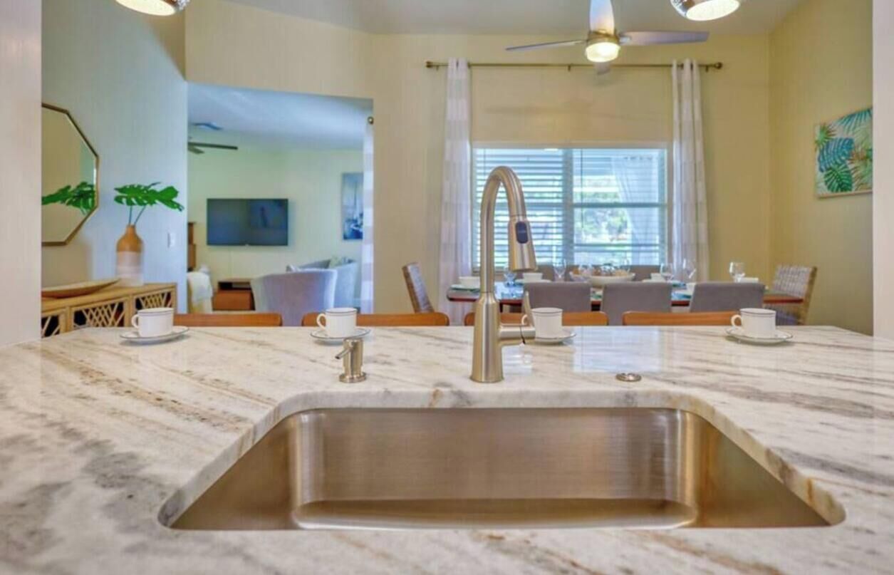 Eine moderne Küche mit einer großen Spüle, einem Essbereich mit Tisch und Stühlen sowie einem Deckenventilator.