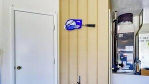 Une pièce avec une porte blanche, un tapis à motifs bleus et blancs, un mur à rayures bleues et blanches, et une étagère avec divers objets.