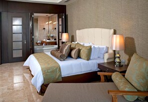 Una habitación de hotel con una cama grande, dos lámparas de noche, una mesita de noche de madera y un sofá.
